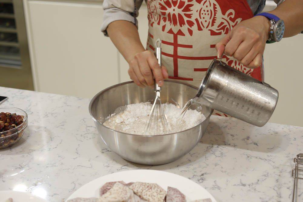 芋頭糕食譜 Step 3：粘米粉、生粉及調味料倒入大盆中，慢慢加入雞湯及水，邊倒邊攪成粉漿狀態，備用。