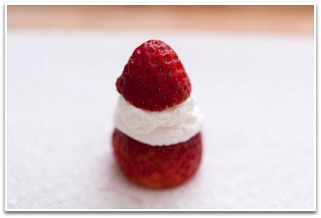 聖誕甜品 3. 蓋上草莓小帽子，再擠上奶油花作裝飾。