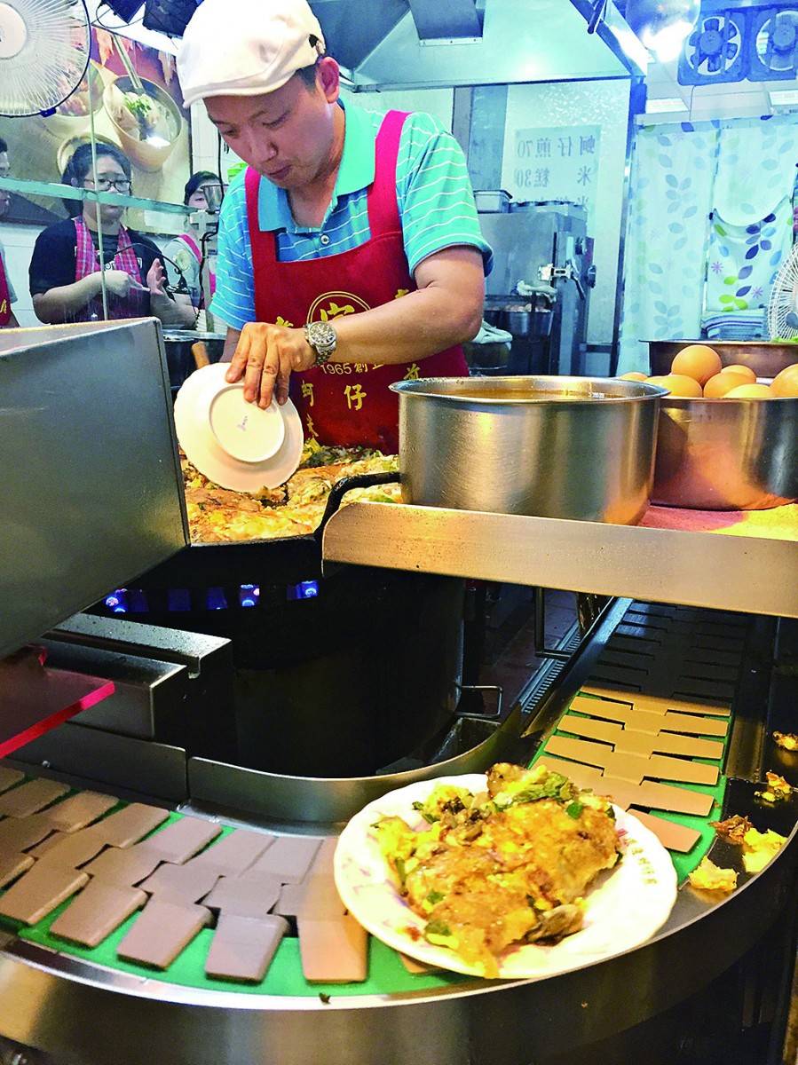台北夜市 在店門口見到師傅不停大鑊大鑊地在做蚵仔煎，煎好就分成一份份，用運輸帶轉出去再加上特調的海山醬。
