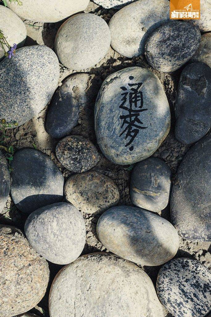 浪遊 隊友們山寨藏人用鵝卵石 堆砌通麥之墓，Yanki 還特 意寫繁體字紀念小狗。