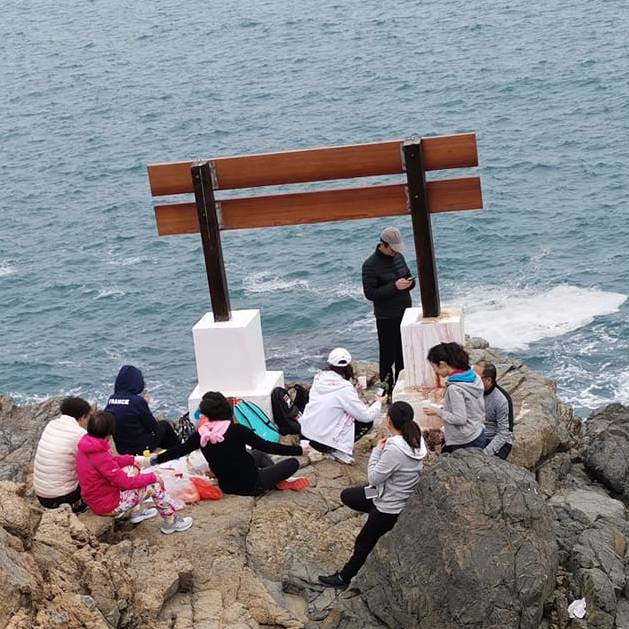 相片中可見一群人於鶴咀打卡位木製指示牌下聚集野餐。