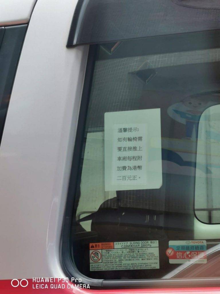 的士 一部混能的士的車窗上所張貼的告示，內容為「溫馨提示：如有輪椅需要直接推上車廂，每程附加費港幣200元正」