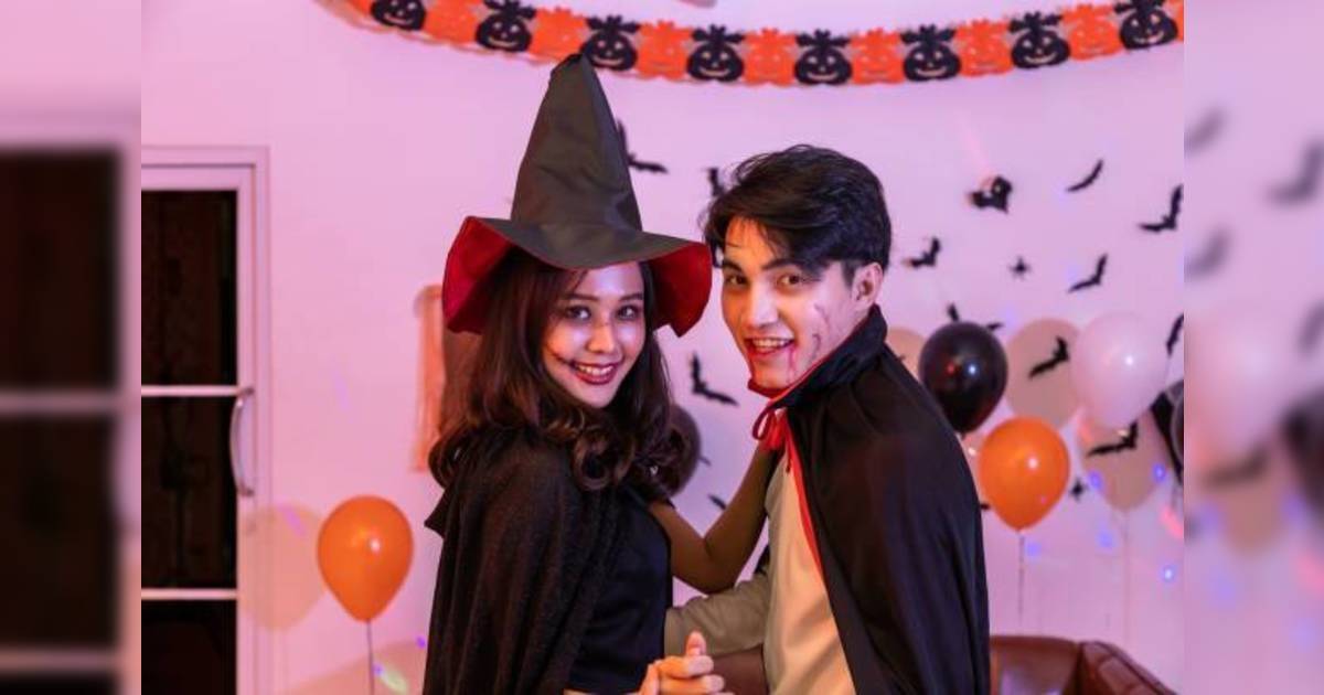 萬聖節裝扮2023 Young happy Asian people couple dressing Halloween costume, vampire and witch, dancing in party. Looking at camera.